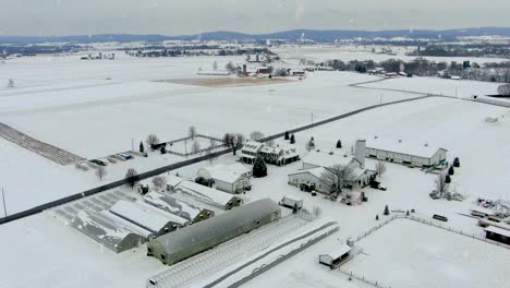 aerial orbit of american farm and greenhouse buildings covered in winter snow