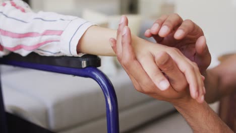 biracial woman in wheelchair holding hands with male partner in living room