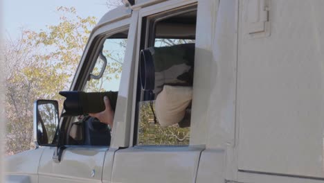 tourists on an african safari taking pictures with professional cameras from a jeep