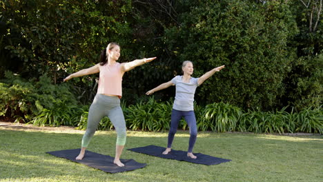 practicing yoga, asian grandmother with granddaughter on yoga mats in garden