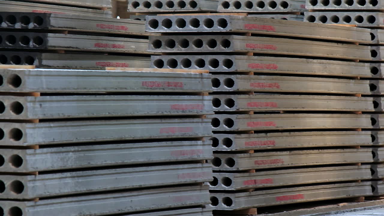 Big piles of armored concrete plates for construction with holes inside. Building materials storage at modern plant.