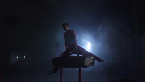 male-gymnast-athlete-performs-handstand-and-spin-on-Pommel-horse-on-a-dark-background-and-smoke-in-slow-motion.-Olympic-programme