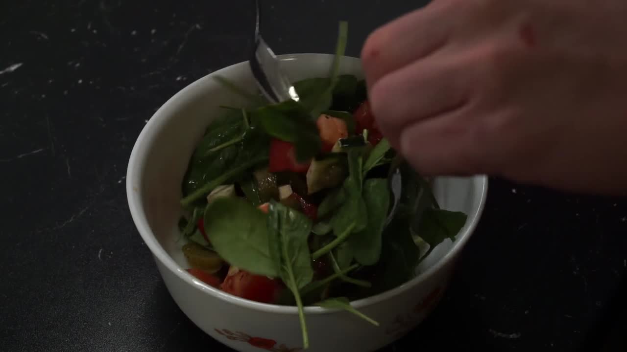 다진 재료가 많은 건강하고 신선한 샐러드 그릇에 맛을 내고 야채를 넣고 숟가락으로 섞습니다.