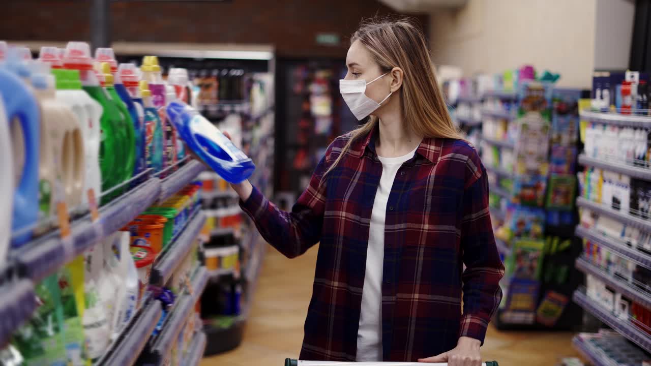 mujer eligiendo detergente en una tienda de artículos para el hogar con máscara