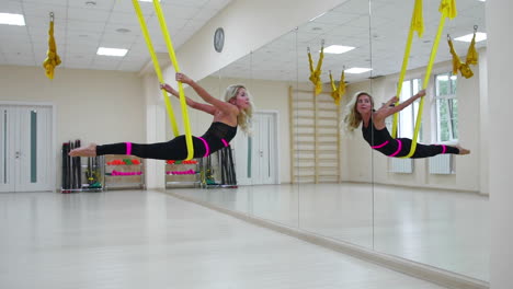 the concept of sports for a healthy lifestyle. the girl has been aerology of antigravity relaxes and swings on the canvas in a white room