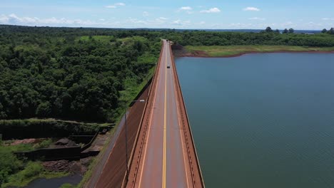 carro atravessando uma incrível estrada solitária em uma bela paisagem tropical com um lago ao lado e uma densa selva do outro lado