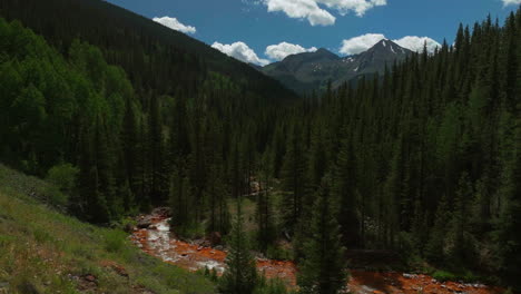 Aerial-cinematic-drone-orange-river-Cement-Creek-summer-high-altitude-downtown-Silverton-Telluride-Prospect-Gulch-Colorado-Rocky-Mountains-stunning-drive-looking-up-steam-forward-slowly-movement