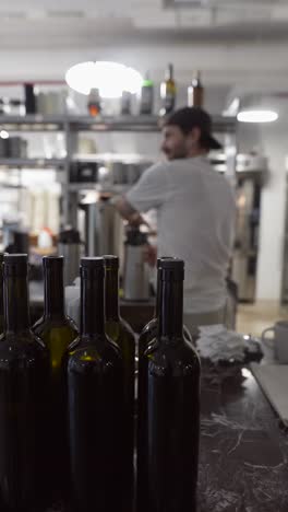botellas de vino y chef en la cocina del restaurante