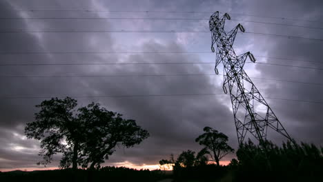 nubes dramáticas sobre líneas eléctricas silhoeutted y pilón, lapso de tiempo