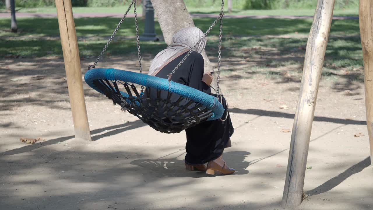 Una mujer en un columpio en un parque.