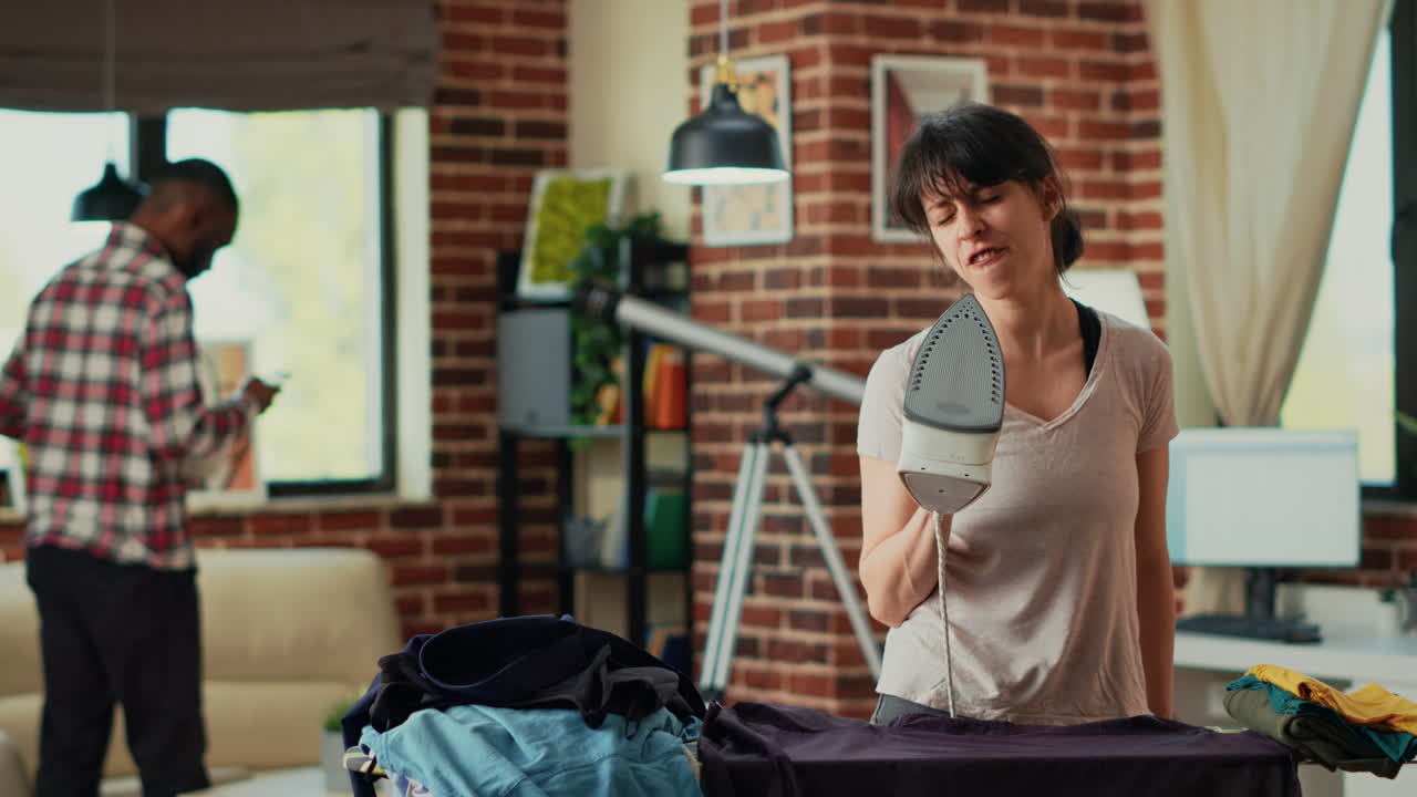 Smiling person singing and dancing while she irons clothing