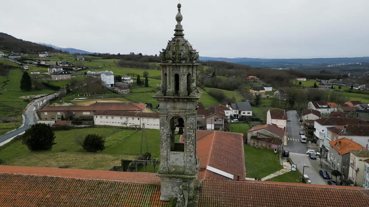el dron orbita alrededor de la torre del campanario de piedra tallada mientras una bandada de pájaros vuela alrededor de santa maría de xunqueira.