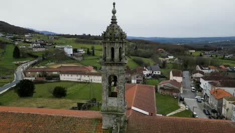 drone orbit around carved stone bell tower as flock of birds fly around santa maria de xunqueira