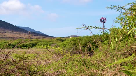 4k-60fps-slow-slider-shot-of-windpumps-standing-and-spinning-in-rural-farm-field-in-the-Caribbean