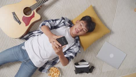 teenage boy relaxing at home with guitar and technology