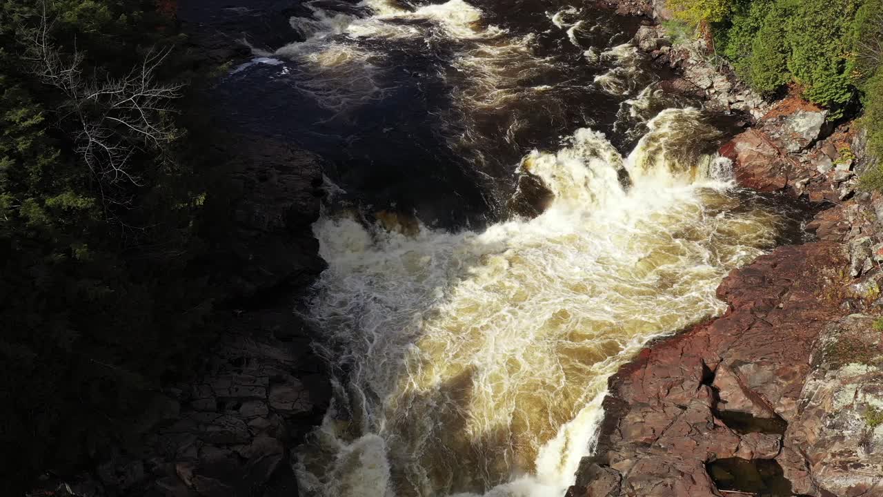 rapids and waterfalls in fall colored forest overhead ascending aerial
