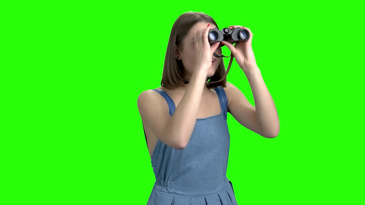 Ragazza adolescente usa il binocolo, vista frontale.
