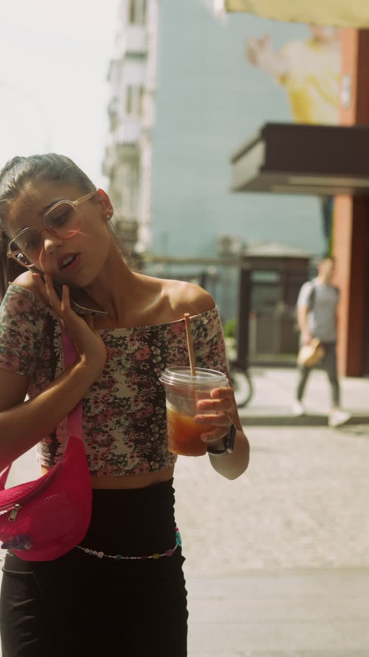 Teenager Talking on Phone and Drinking Drink in City