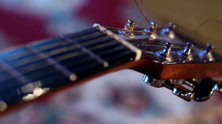 Bir bas gitarın telleri, gövdesi, ışık yansımaları ve gitar üzerindeki odak kayması ile büyük bir yakın çekim