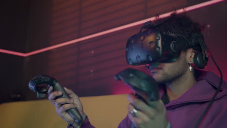 close up view of boy playing video games wearing virtual reality glasses and using gamepads sitting on sofa at home