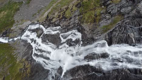 Drone-diving-out-from-cliff-and-following-mountain