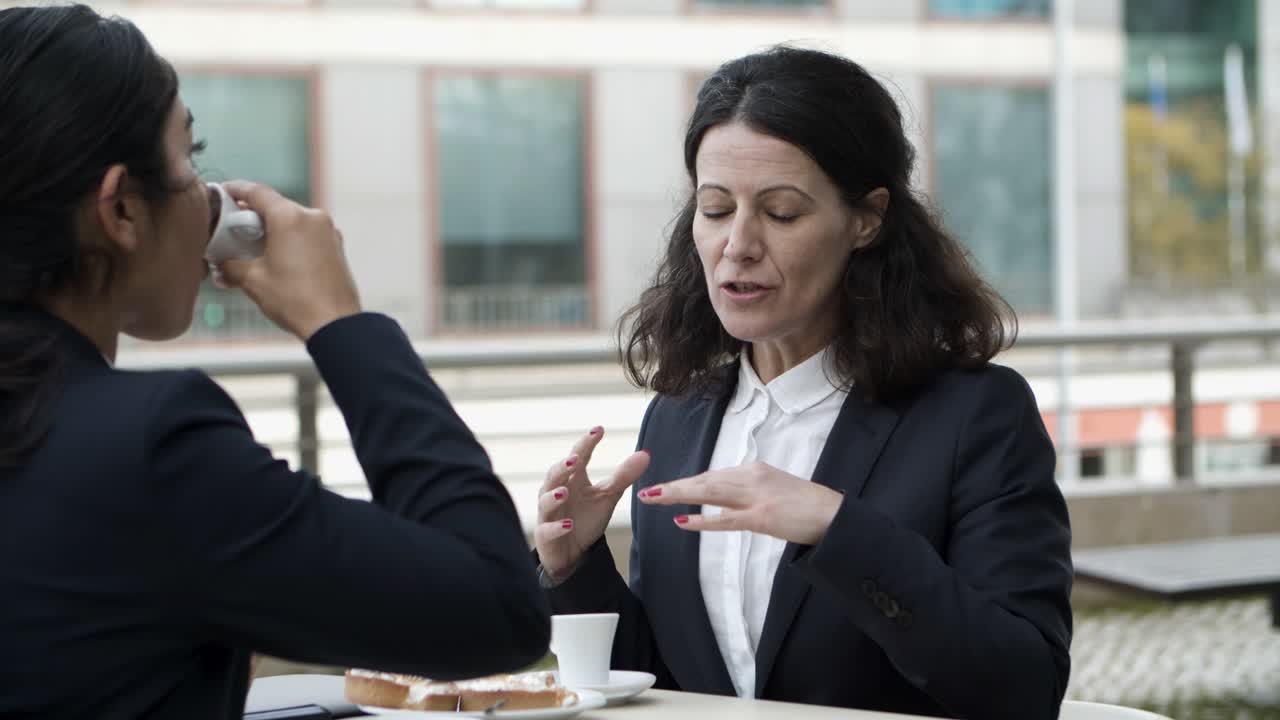 mulheres de negócios a falar num café ao ar livre.