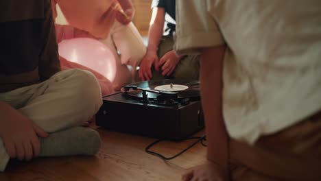 A-group-of-preschool-children-sit-in-a-circle-and-look-at-the-record-player-and-listen-to-music.-Interested-children-look-at-a-record-player-in-a-club-preparing-children-for-school