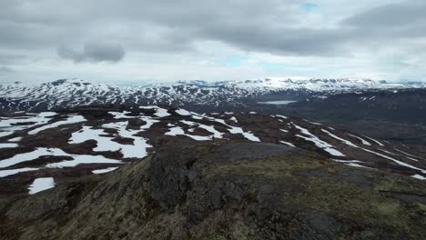 Vista-Aérea-De-Una-Persona-Parada-En-La-Cima-De-Una-Colina-En-El-Parque-Nacional-Hardangervidda-Sobre-Paisajes-Cubiertos-De-Nieve