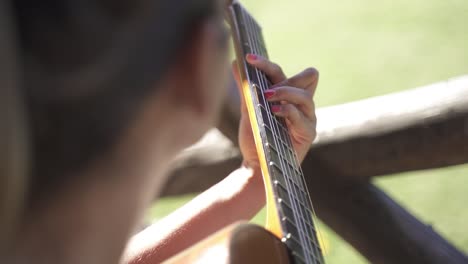 Mujer-Joven-Amablemente-Tocando-La-Guitarra-Al-Aire-Libre-Primer-Plano-De-La-Luz-Del-Día-Cámara-Lenta-Y-60fps