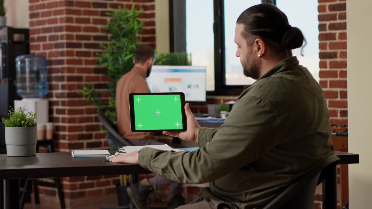 Company employee looking at tablet with horizontal greenscreen
