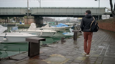 man walking along a canal dock in italy