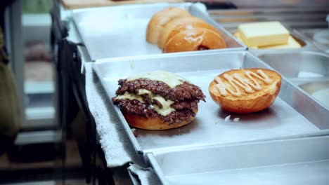 Imágenes-Cinematográficas-De-Cocina-De-Comida-De-4k-De-Un-Chef-Preparando-Y-Haciendo-Una-Deliciosa-Hamburguesa-Casera-En-La-Cocina-De-Un-Restaurante-En-Cámara-Lenta-Poniendo-Las-Hamburguesas-Con-Queso-En-El-Pan