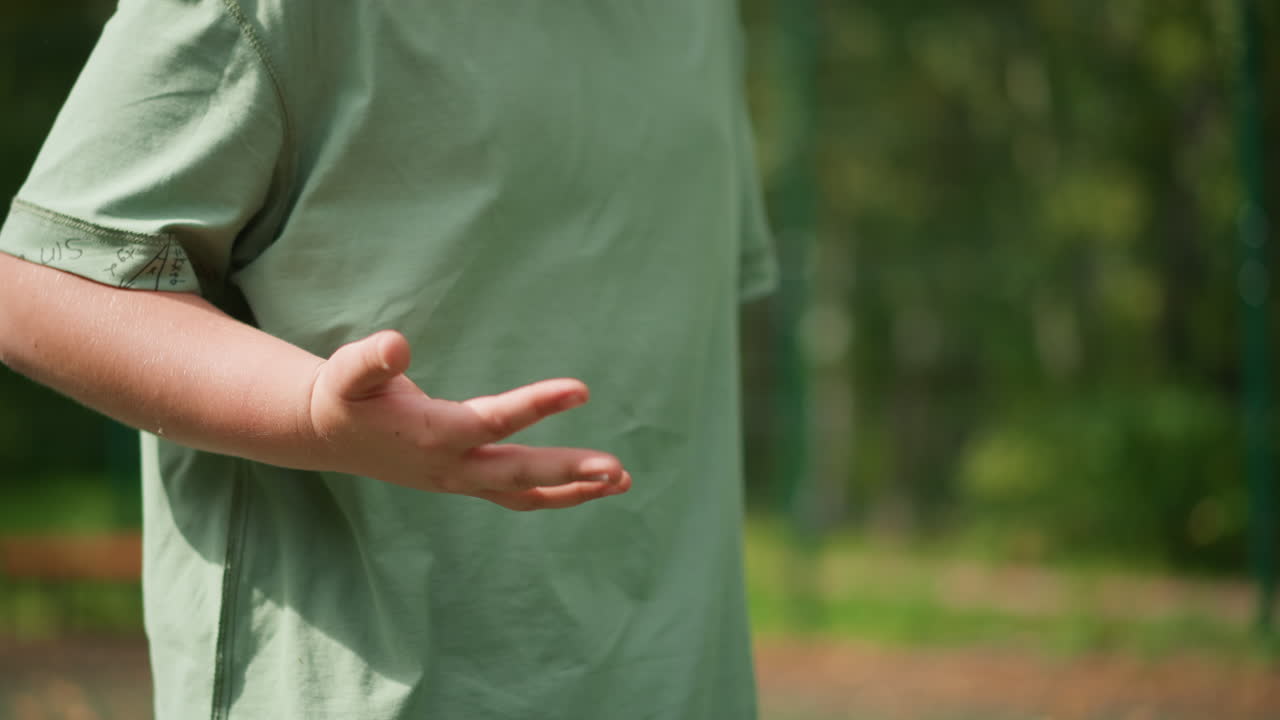 Caucasian Child Tossing Pink Ball Outdoors, Midair Freeze Of Small Toy Ball Above Palm, Casual Green Shirt And Forest Backdrop, Playful Motion And Summer Sunlight, Youthful Practice And Simple