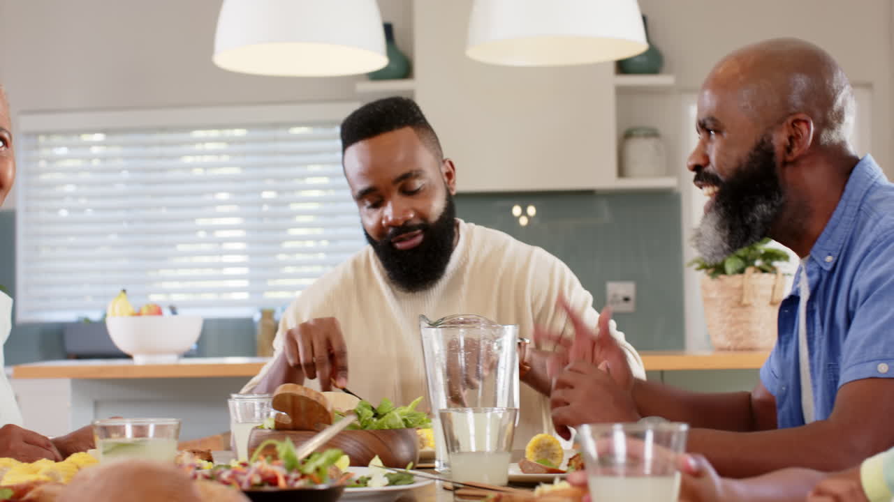 Eating together, multi-generational african american family enjoying meal and conversation at home