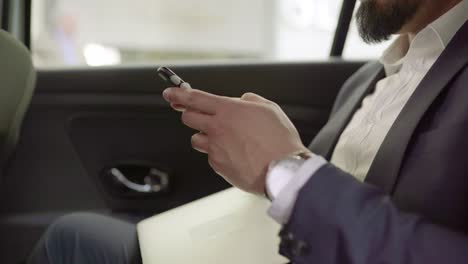 businessman messaging by cell phone in taxi