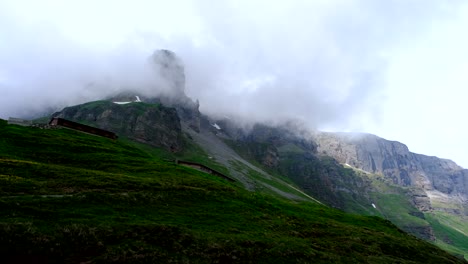 un paisaje de vegetación con una montaña rocosa y nubes por encima