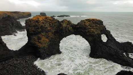 the beautiful black rock arch formation at diamond beach in iceland by the sea - wide shot