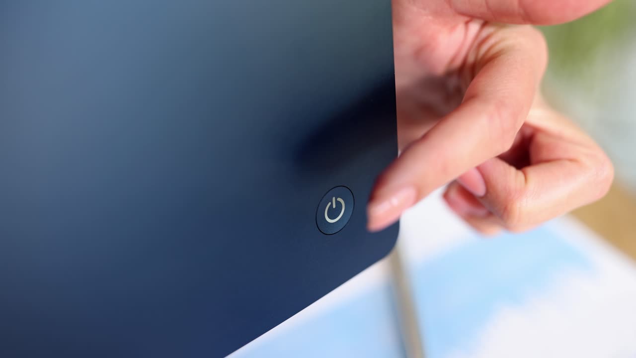 Close-up of a hand pressing a power button on an electronic device