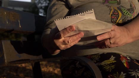 hands of mature woman holding letter in the park close up shot