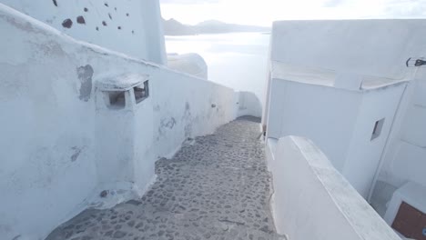 Walking-down-an-empty-white-street-in-Oia,-Santorini