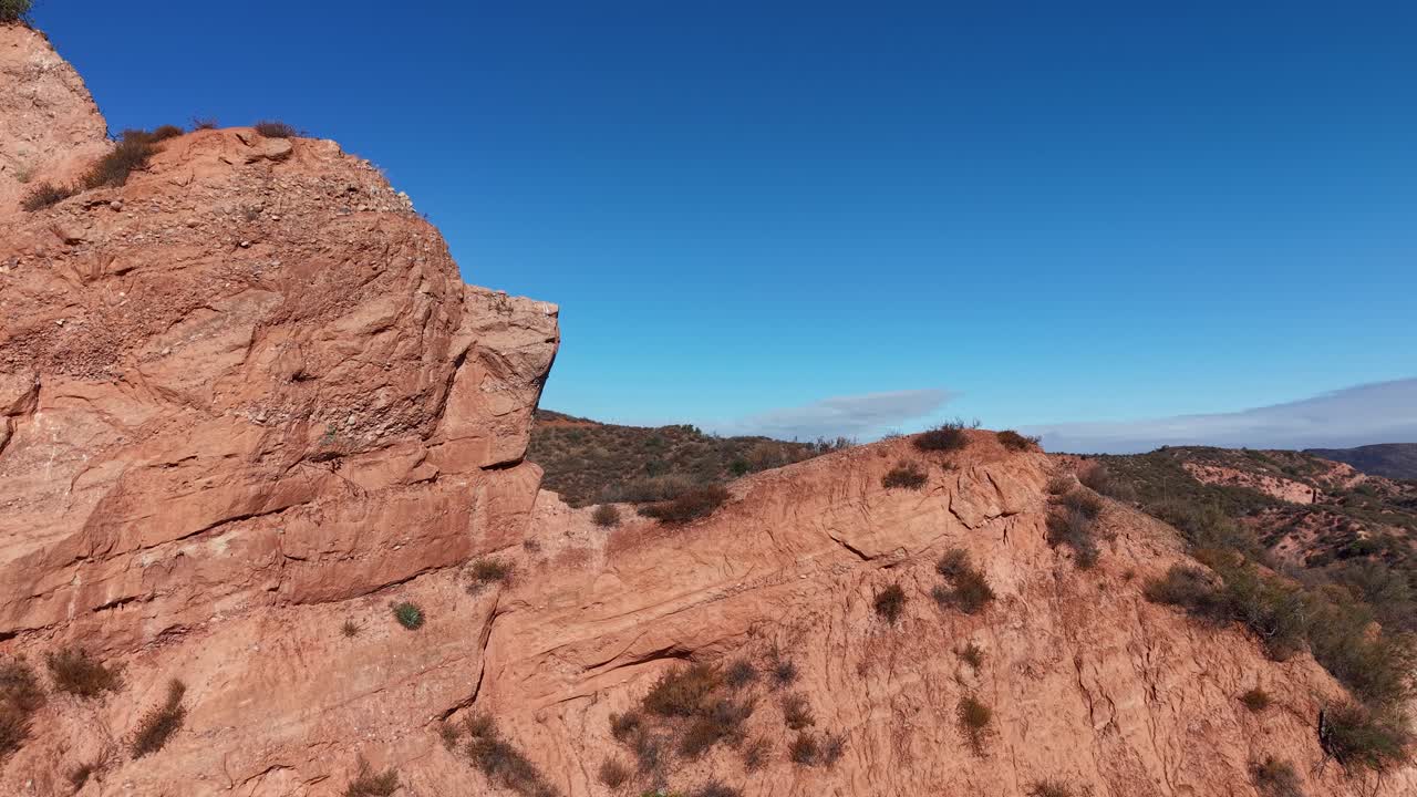 Drone view of dramatic sandstone formations in Black Star Canyon, California, highlighting the rugged, arid terrain and distinct layers of exposed rock under clear blue skies