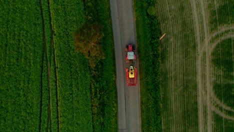 tractor driving on tarmac between farm roads - drone aerial top-down shot