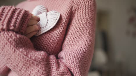 hands young woman holding baby booties. knitted shoes handmade for babies