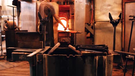 mid section of glassblower shaping a molten glass