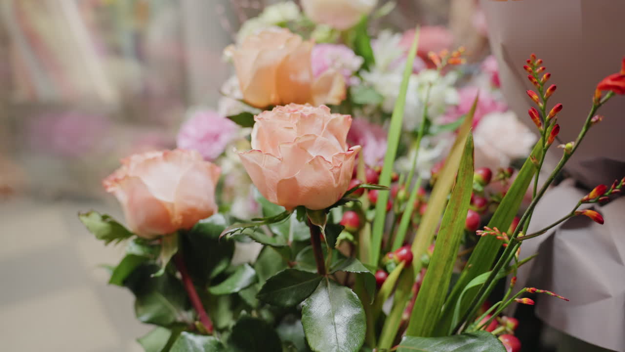 Ambiente íntimo de boutique presentando detallados ramos de rosas coral. Rosas coral arregladas con hojas reflectantes y delicadas gotas en los pétalos crean un ambiente íntimo en estilo boutique.