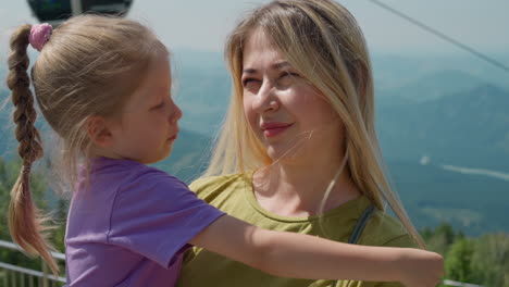 little girl hugs smiling mother at aerial lift station