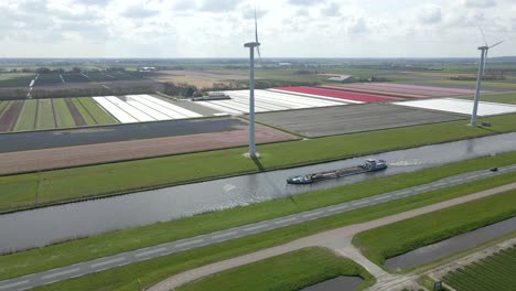 Buque-De-Carga-Se-Mueve-A-Través-De-Un-Canal-Recto-En-El-Campo-Holandés-Con-Molinos-De-Viento