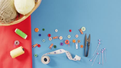 video of dressmaking equipment with orange fabric and wool on blue background with copy space