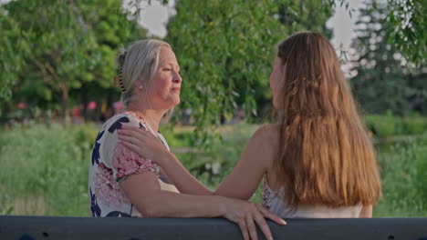 a young woman shares a tender moment with her mother on a park bench, ending in a heartfelt hug. shot in natural light, full of love, trust, and emotional warmth