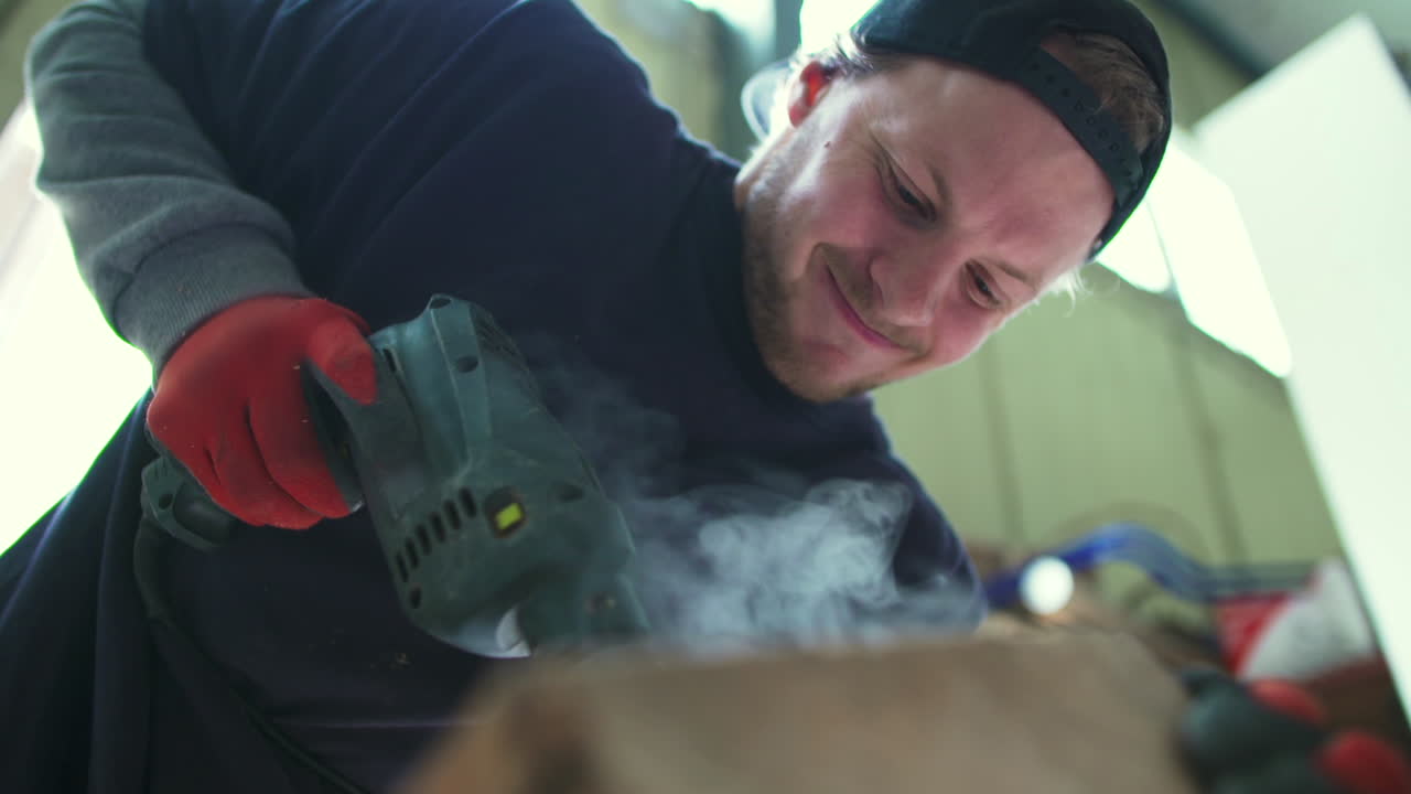 Happy Man Drilling Wood with a Power Tool in a Workshop
